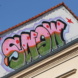 Graffiti-Schriftzug an Hausgiebel.