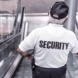 Security-Mann auf Rolltreppe, Rückenansicht.