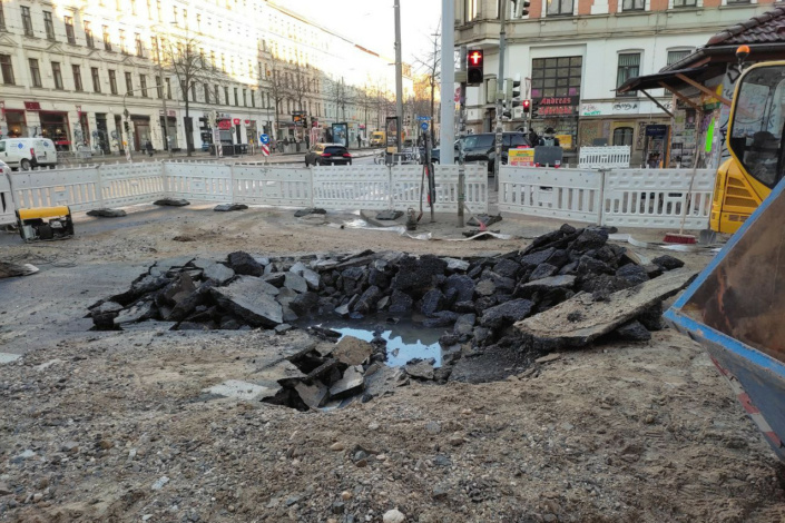 Gesperrte Straße mit aufgeplatztem Untergrund und Wasser.