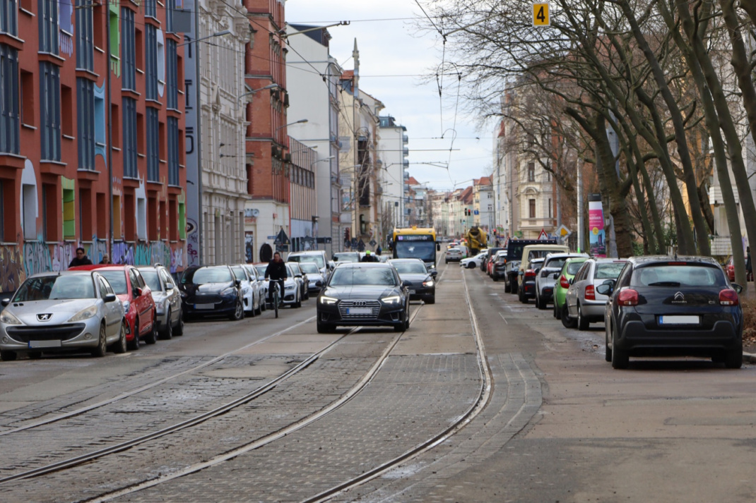 Verkehrsstraße mit Tram-Schienen und parkenden PKW.