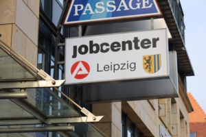 Hinweisschild des Jobcenters Leipzig mit Wappen an Hauswand.