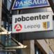 Hinweisschild des Jobcenters Leipzig mit Wappen an Hauswand.