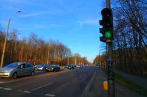 Verkehrsstraße mit sich stauendem Verkehr, Ampel und blauer Himmel.