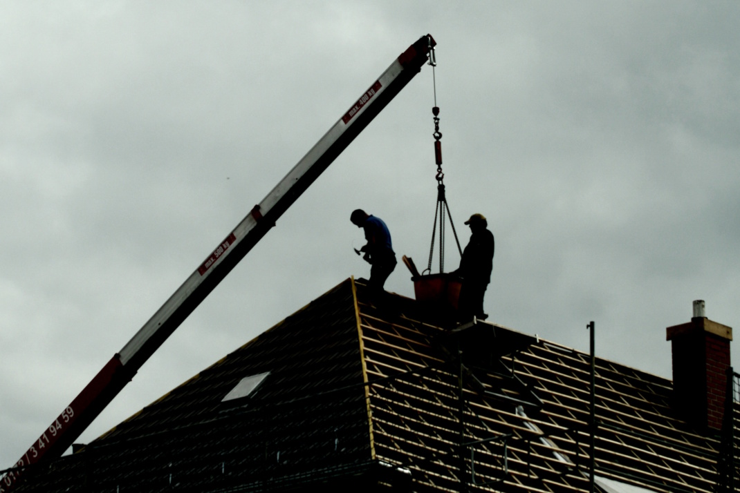 Arbeiter auf einem Hausdach.