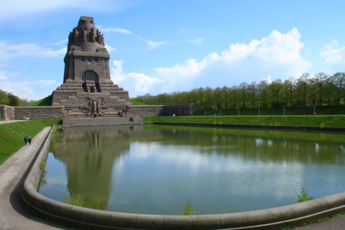 Völkerschlachtdenkmal mit vorgelagertem Teich, blauer Himmel und Wolken.