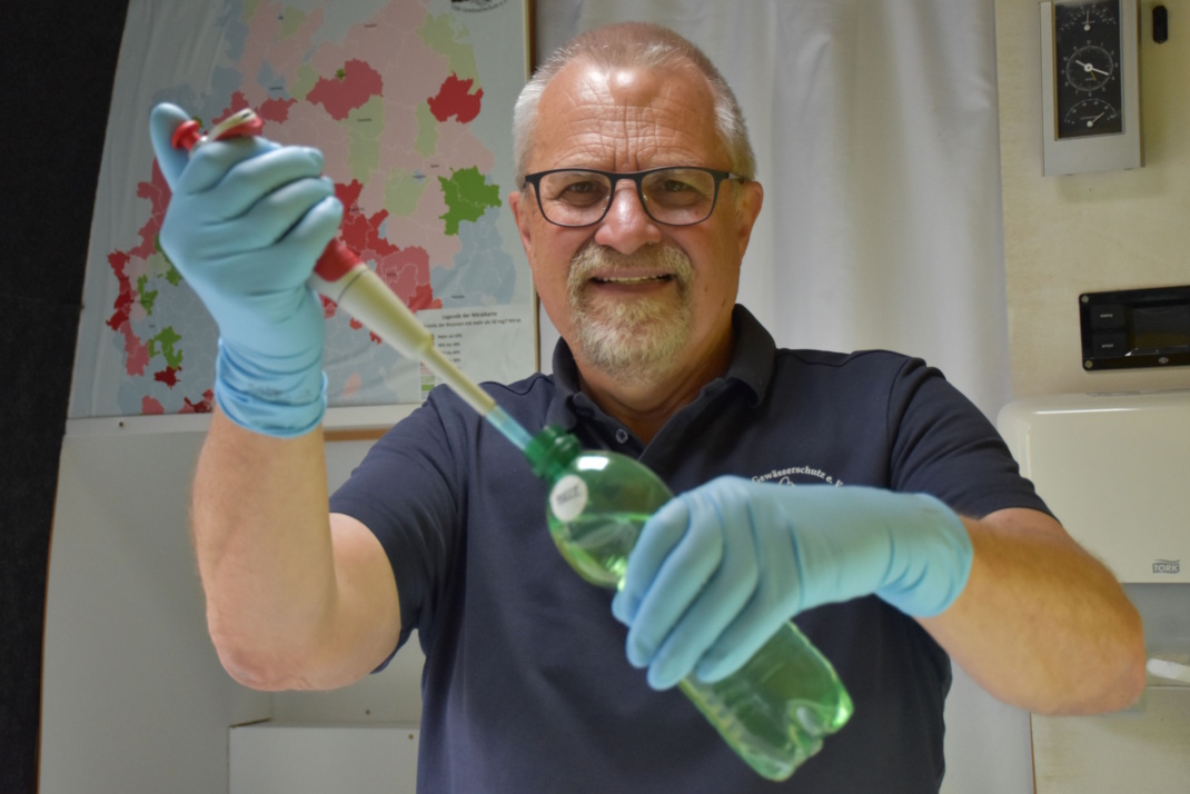 Mann mit Handschuhen und Wasserprobe im Labor.