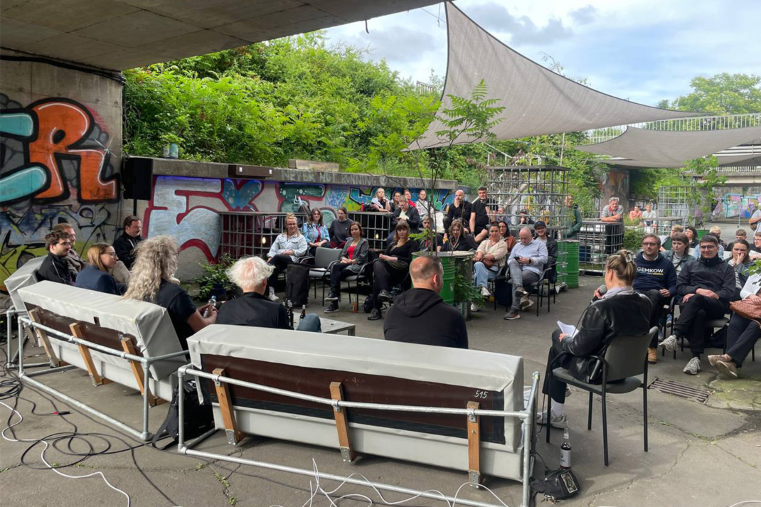 Podiumsdiskussion im Freien mit Front und Zuhörern.