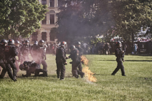 Polizeibeamte auf Wiese, Uniform hat nach Angriff Feuer gefangen.