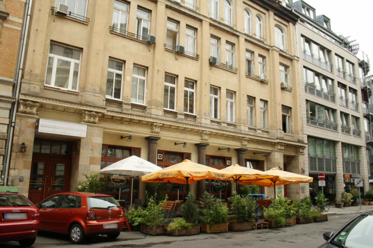 Hausfassade eines Altbaus mit Freisitz und parkenden PKW.