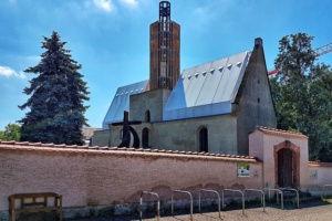 Kirchgebäude hinter Ummauerung, blauer Himmel.