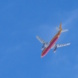 DHL-Flieger von unten im Flug, blauer HImmel.