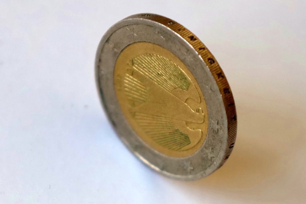 Zwei-Euro-Stück steht auf der Kante, Nahaufnahme von oben.