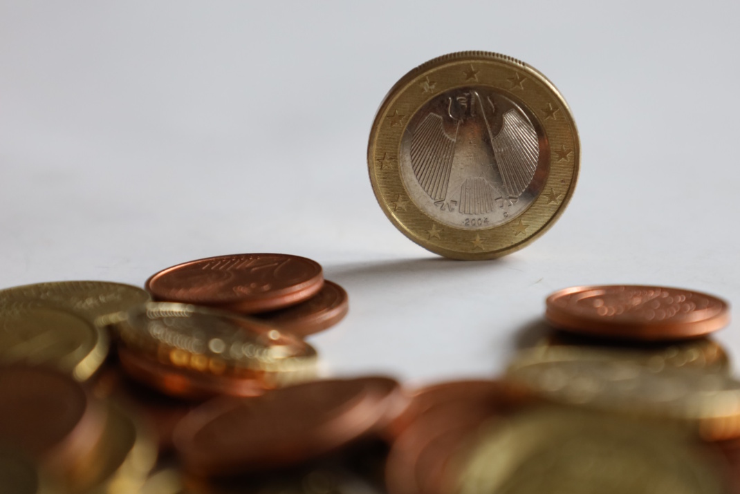 Euro- und Centmünzen in Nahaufnahme, Ein-Euro-Stück steht auf der Kante.
