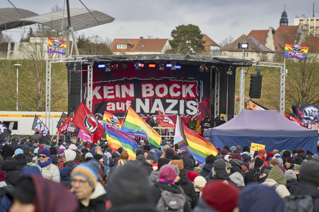 Protestveranstaltung gegen AfD, Menschen haben sich mit Flaggen vor einer Bühne versammelt.
