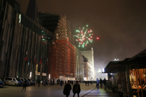 Silvester-Feuerwerk, davor ein Platz mit Menschen.