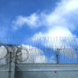 Stacheldraht an Gefängnis, Himmel mit Wolken dahinter.