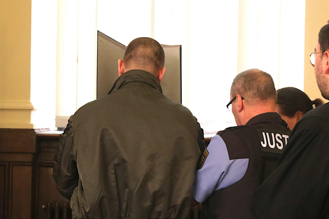 Angeklagter im Gerichtssaal des Landgerichts, Rücken zugewandt.