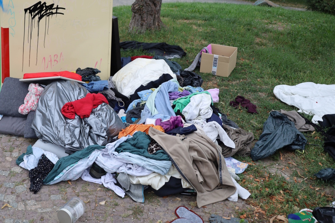Kleidercontainer, davor ein aufgeschichteter Haufen Sachen.