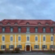 Frontalaufnahme eines Hauses mit gelber Fassade und rotem Dach.