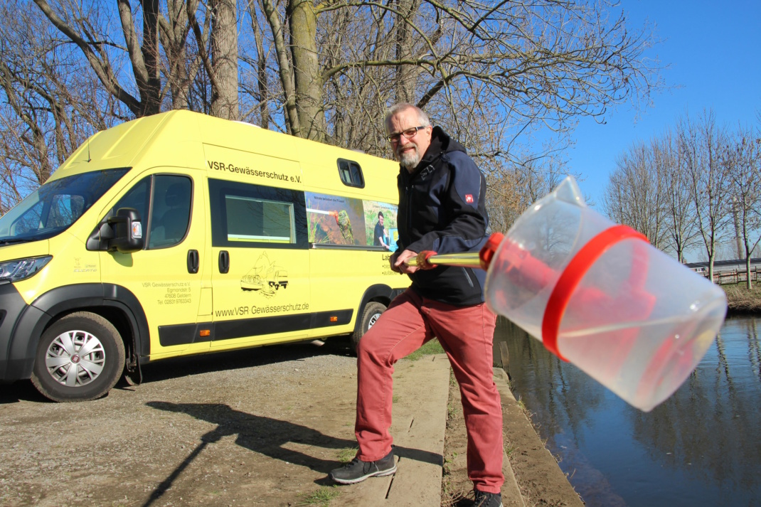 Gelber Wagen, Entnehme einer Wasserprobe aus einem Fluss durch einen Mann daneben.