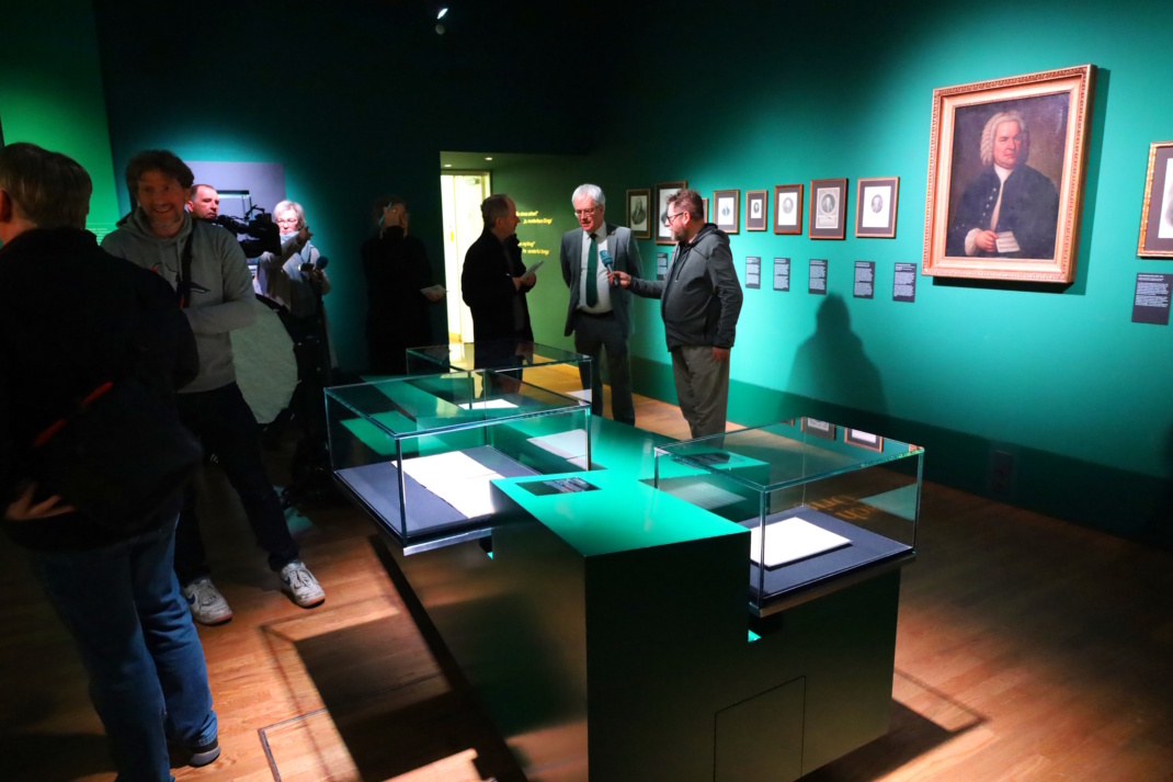 Ausstellungseröffnung, Personen stehen in halbdunklem Museumsraum.