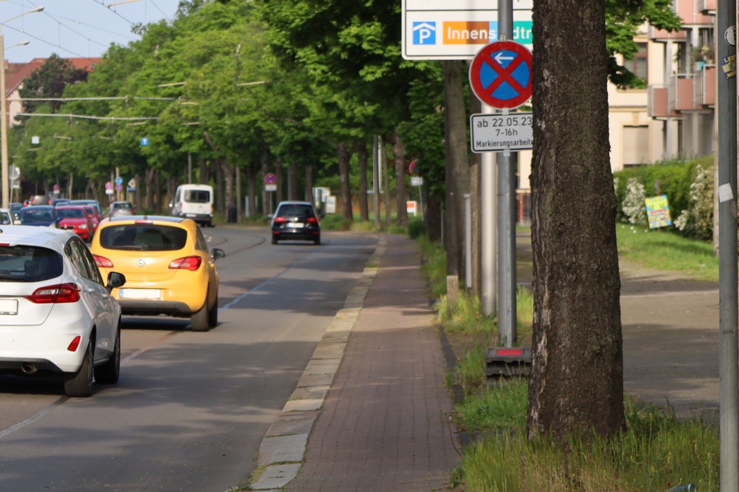 Hauptverkehrsstraße mit fahrenden Autos und schmalem Radweg.