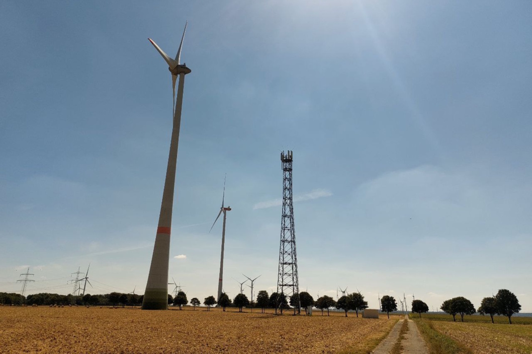 Windkraftanlagen in der Landschaft, blauer Himmel.