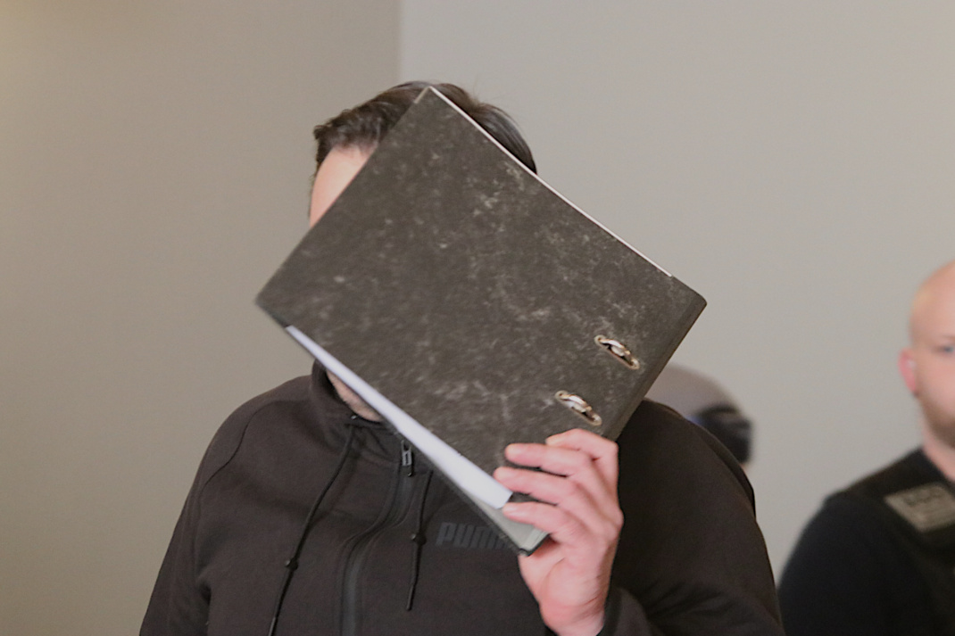 Angeklagter, der sein Gesicht verdeckt.