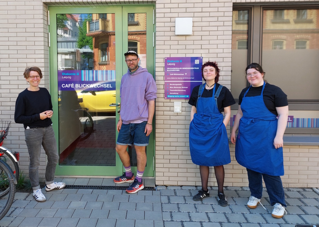 „Blickwechsel“-Leiterin Mirjam Heeger (l.) mit Mitarbeitenden vor dem Eingang zur Beratungsstelle und dem Café Blickwechsel. Foto: PSGZ Blickwechsel