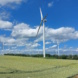 Landschaft mit Windrädern, Wolken und blauer Himmel.