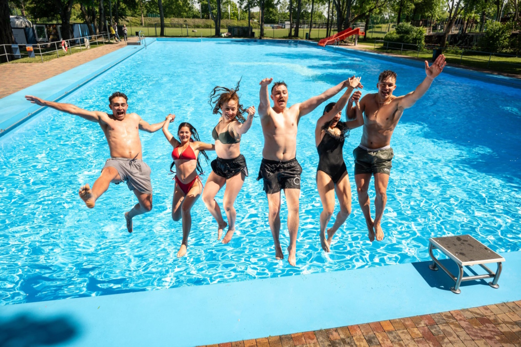 Gruppe von sechs Badegästen, die rückwärts ins Wasserbecken springt.