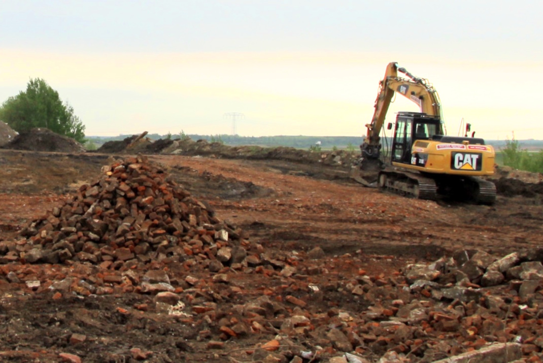 Bauland, gelber Bagger am Rand.
