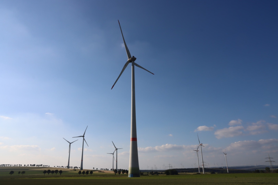 Windkraftanlagen auf freiem Feld, blauer Himmel.