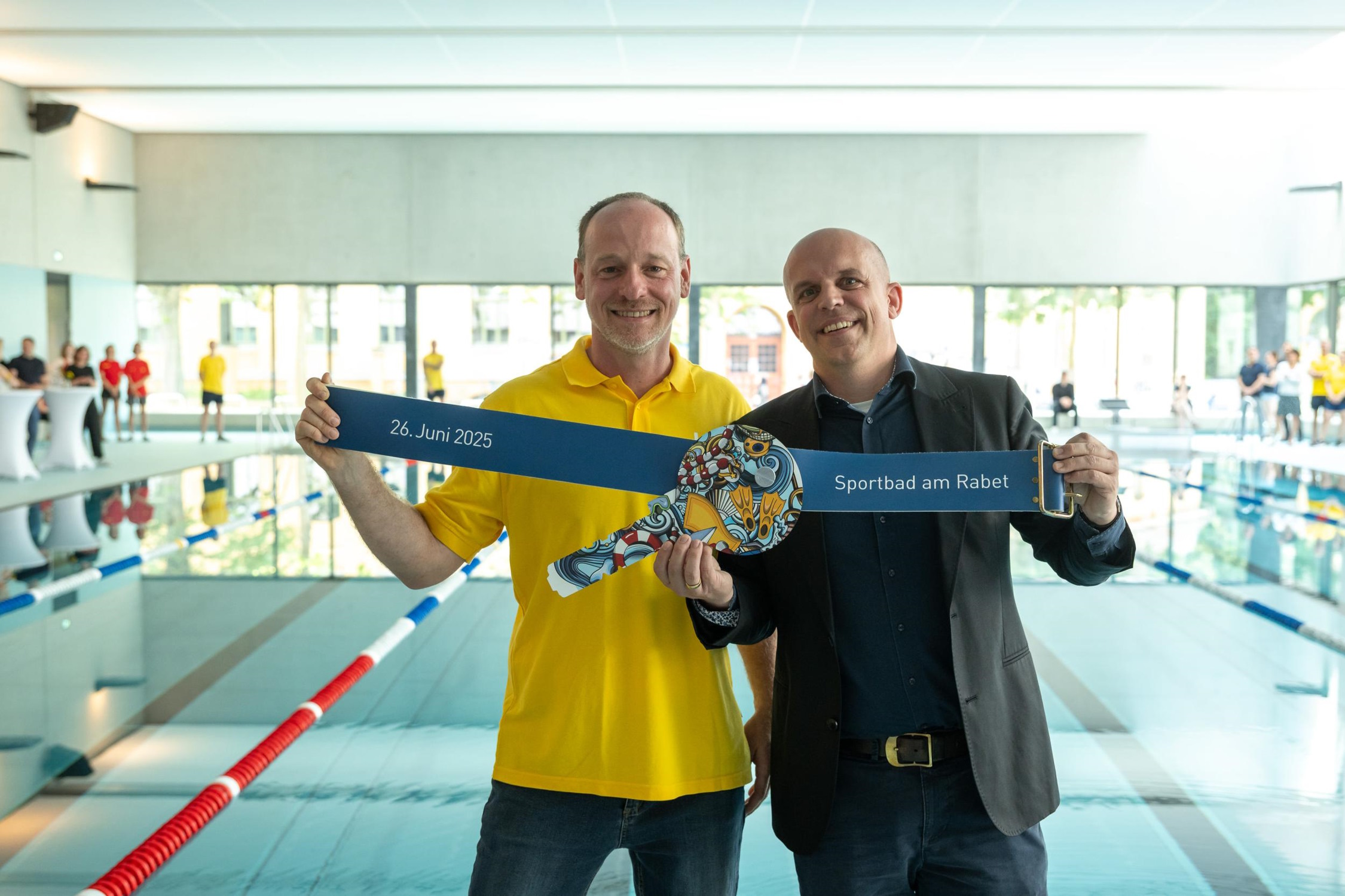 Symbolische Schlüsselübergabe im Sportbad am Rabet: Der leitende Architekt Tobias Keyl (gmp, r.) übergibt einen überdimensionalen Spindschlüssel an den zukünftigen Badleiter Kay Leichsenring (l.). Foto: Leipziger Gruppe
