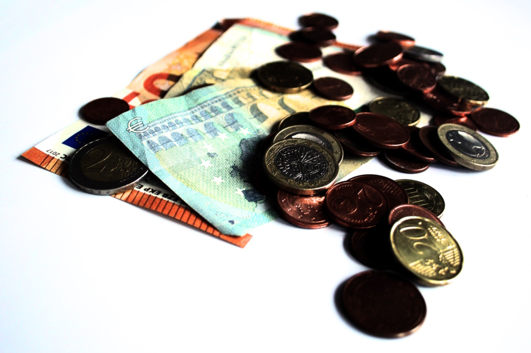 Geldscheine und Geldmünzen auf heller Fläche.