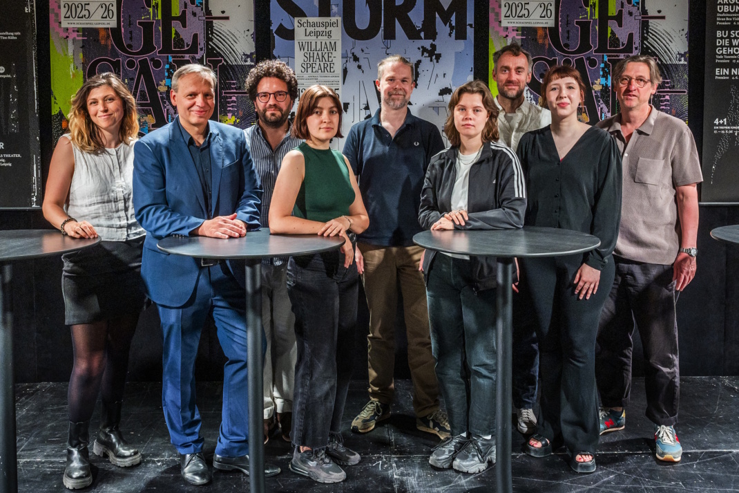 Menschengruppe, die sich an zwei Tischen aufgestellt hat.