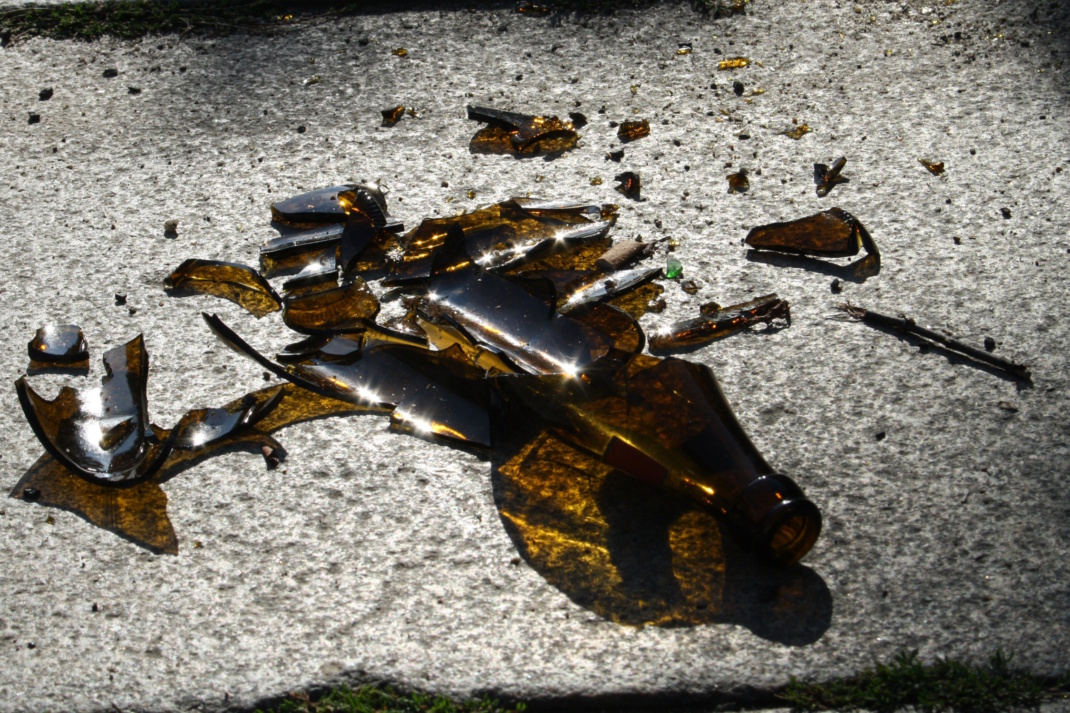 Zerbrochene Flasche und Scherben auf dem Boden.