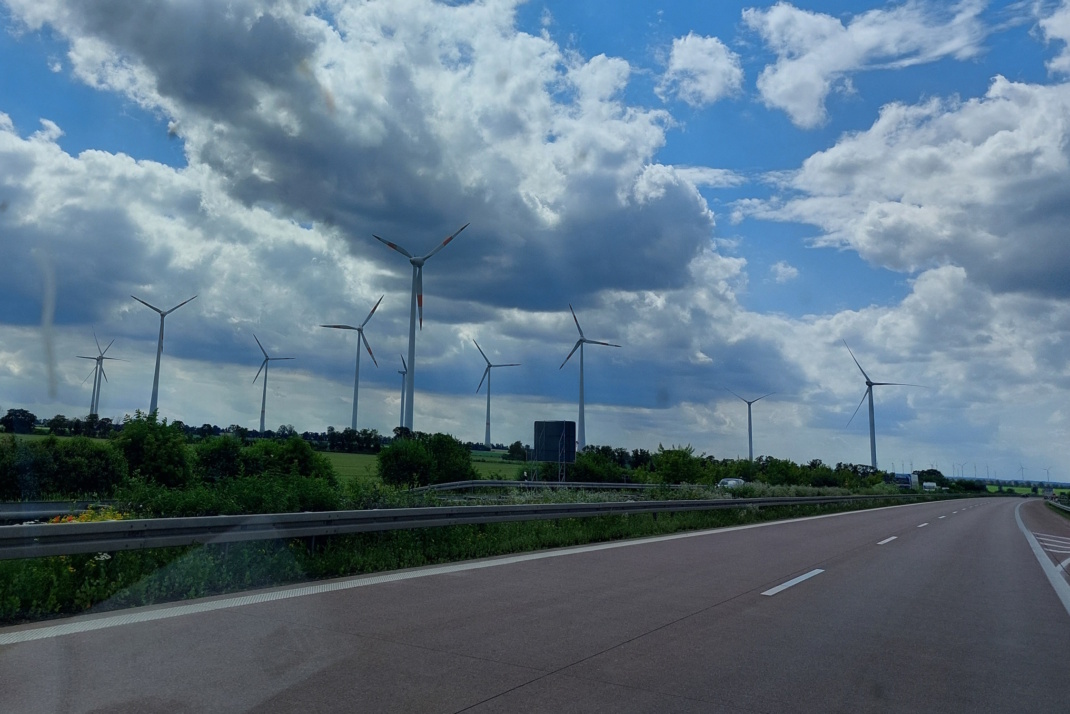 Windräder an einer Autobahn, weiße Wolken am Himmel.