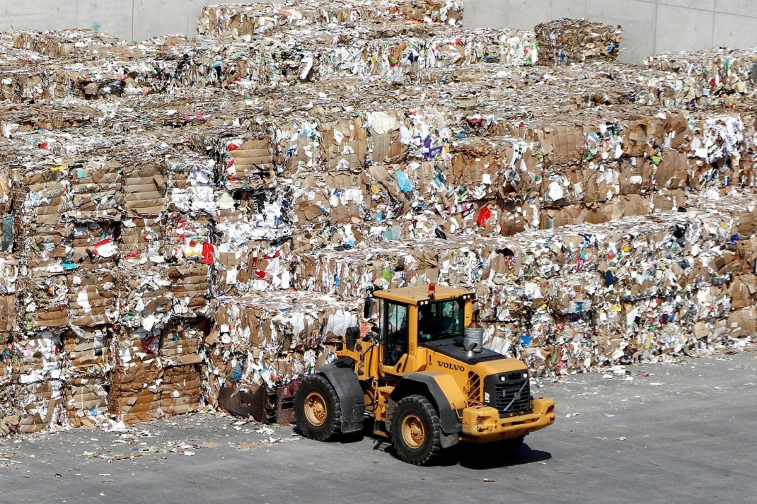Berge von Altpapier zum Recycling mit Gabelstapler im Vordergrund