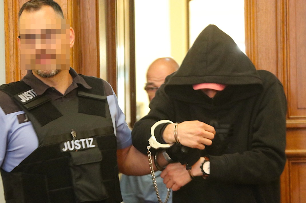 Justizbeamte führen Angeklagten herein.