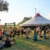 Menschen sammeln sich auf der Wiese vor einem Zirkuszelt.