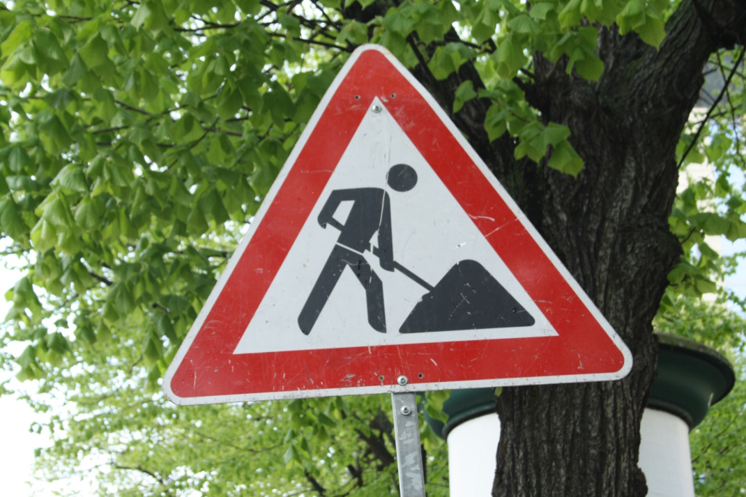 Baustellenschild vor Bäumen.