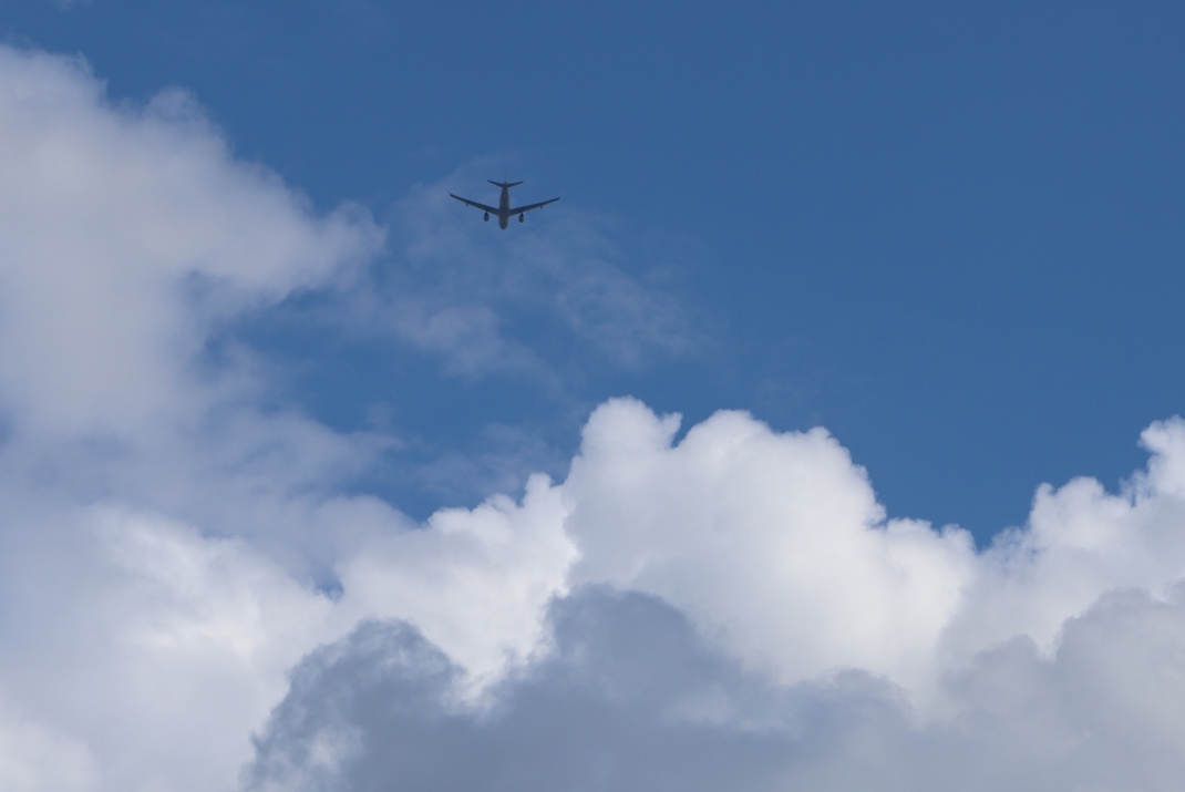 Flugzeug am Himmel, weiße Wolken.