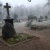 FRiedhof im Nebel, Gräber und Bäume, im Vordergrund Grabmal mit Kreuz.