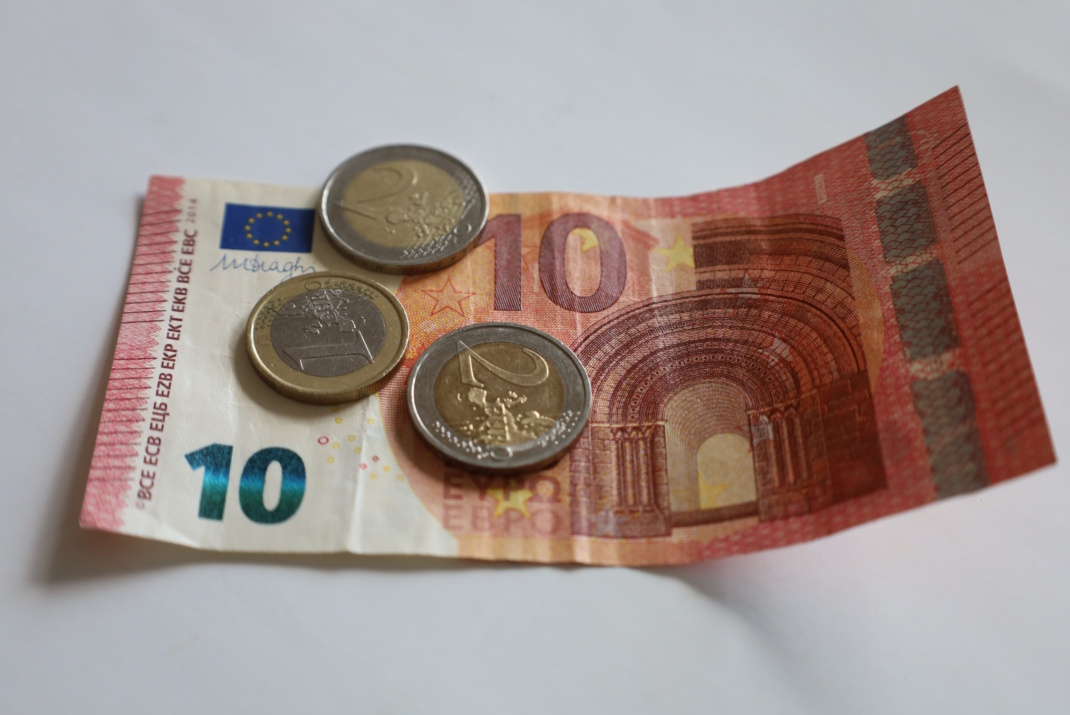 15 Euro als Schein und Münzen liegen auf einer hellen Fläche.