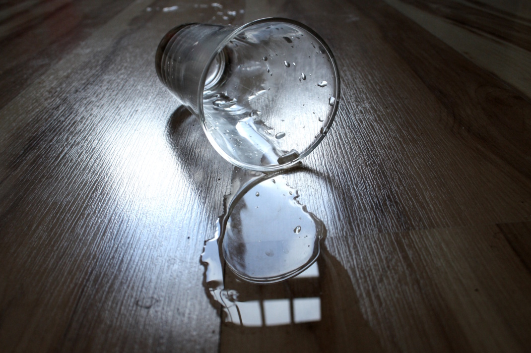 Umgefallenes Trinkglas und ausgelaufener Inhalt.