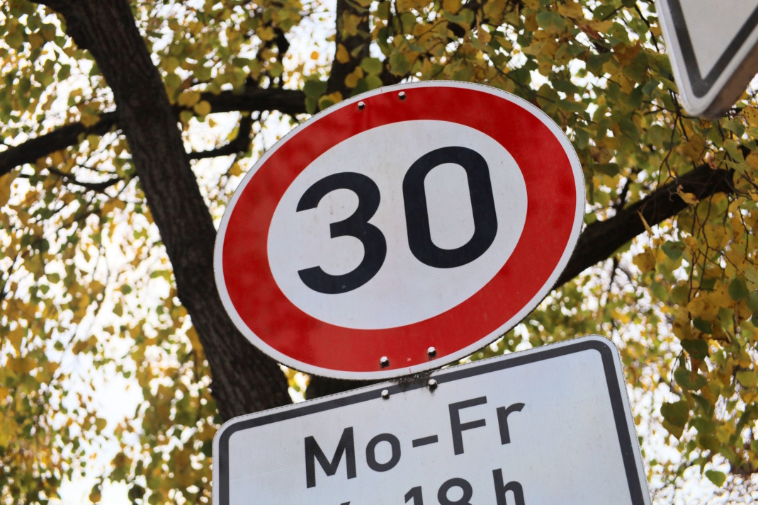 Tempo 30-Schild vor einem Baum, fotografiert von schräg unten.