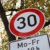 Tempo 30-Schild vor einem Baum, fotografiert von schräg unten.