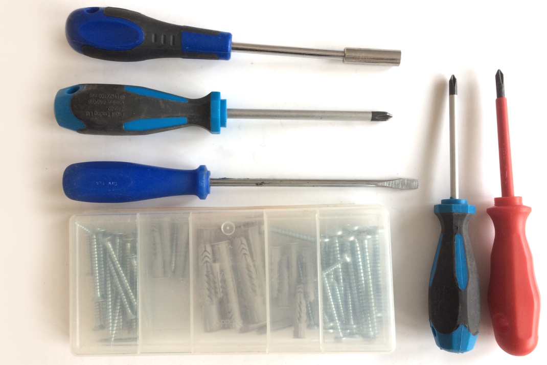 Schraubendreher und Schrauben liegen aufgereiht auf einer Fläche.