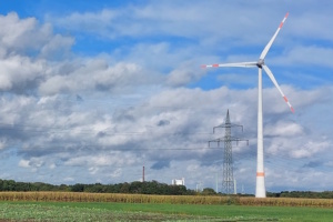 Windkraftanlage auf freiem Feld, Wolken und blauer Himmel.